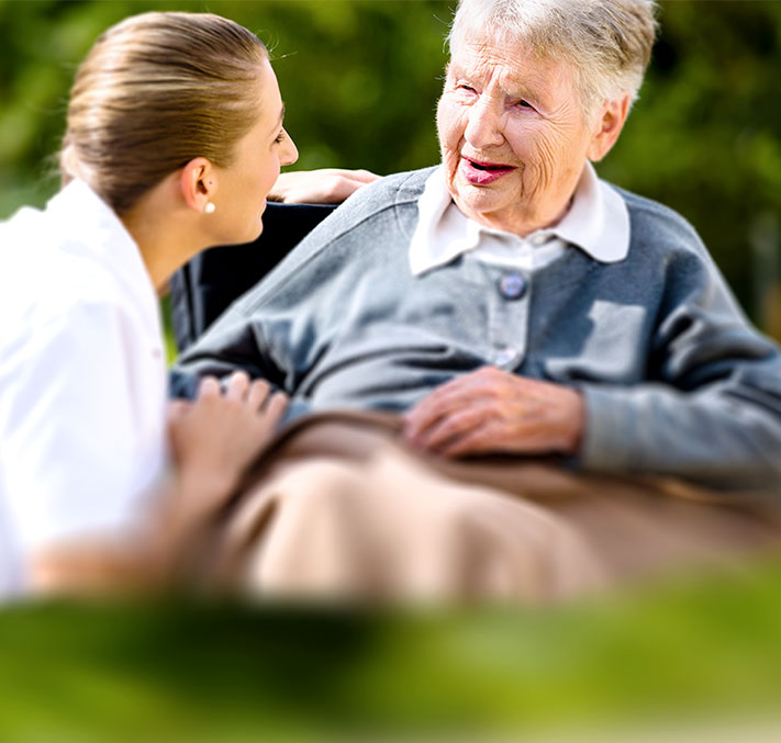 Seniorin mit Pflegeperson im Park