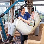 Seniorin in Lifter mit Pflegerin