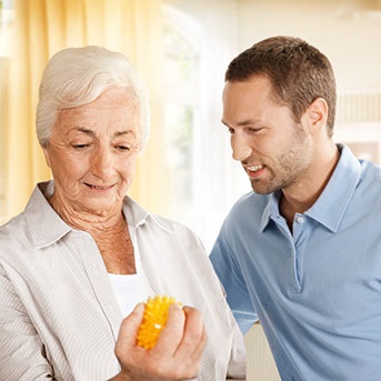 Seniorin drückt Ball mit Pfleger als Kontinenz-Übung