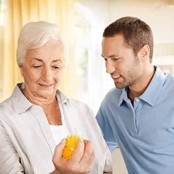 Seniorin drückt Ball mit Pfleger als Kontinenz-Übung