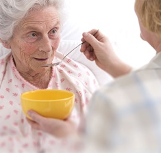 Seniorin wird im Bett gefüttert