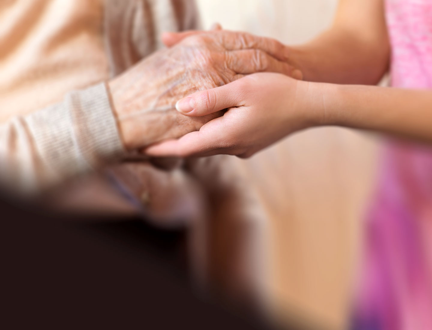 Ältere und junge Hände halten sich gegenseitig