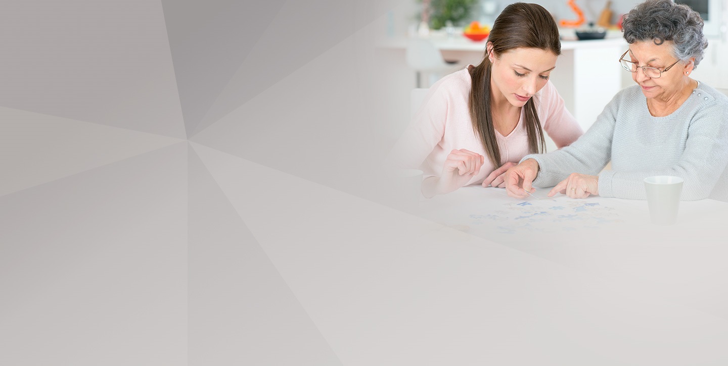 Seniorin puzzelt mit Pflegerin