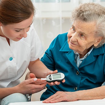 Pflegerin misst Blutzuckerspiegel bei Seniorin