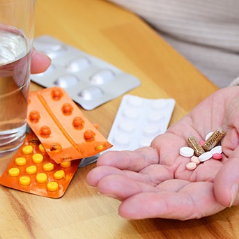 Abbildung von vielen verschiedenen Tabletten in den Händen einer älteren Person