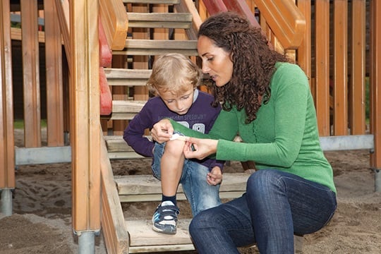 Mutter versorgt Schürfwunde ihres Kindes