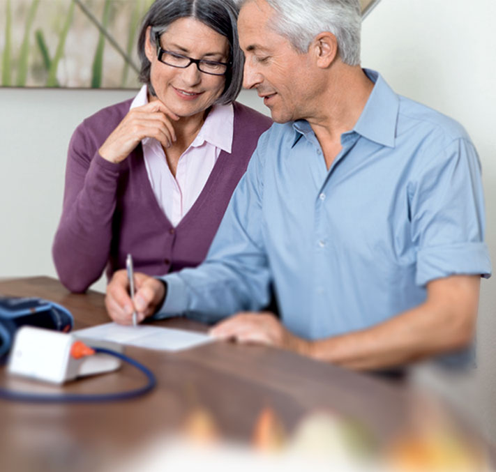 Älteres Paar schreibt aktuelle Blutdruckwerte auf