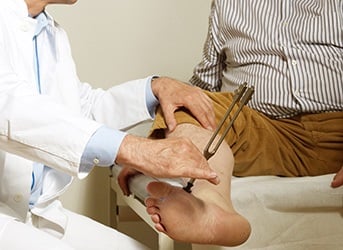 Untersuchung der Reflexe am Bein mit Stimmgabel