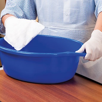 Pflegerin hält Wanne und Waschlappen in der Hand