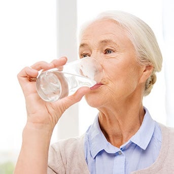 Seniorin trinkt ein Glas Wasser
