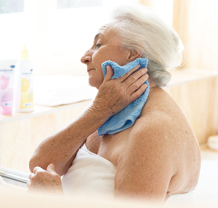 Seniorin wäscht sich mit Waschlappen