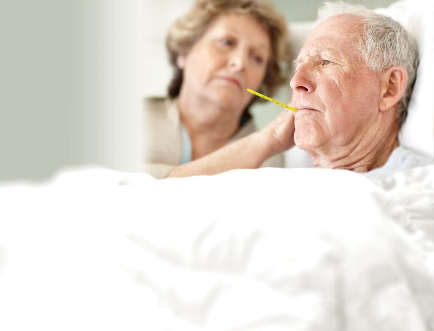 Seniorin und Pflegeperson betrachten Fieberthermometer