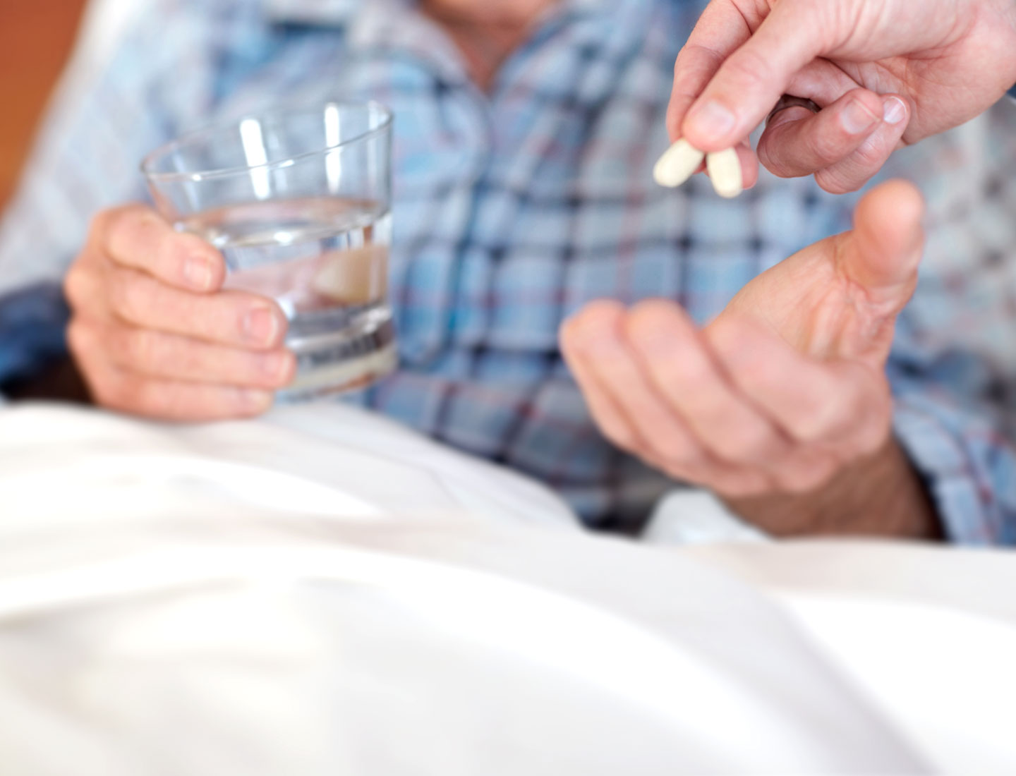 Pflegebedürftiger Senior bekommt Tabletten in die Hand gelegt
