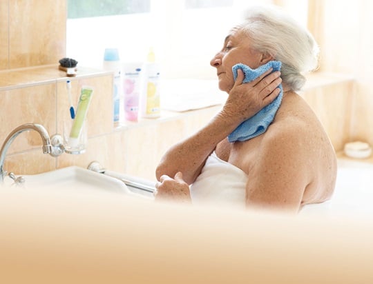 Seniorin wäscht sich selbst mit einem Waschlappen