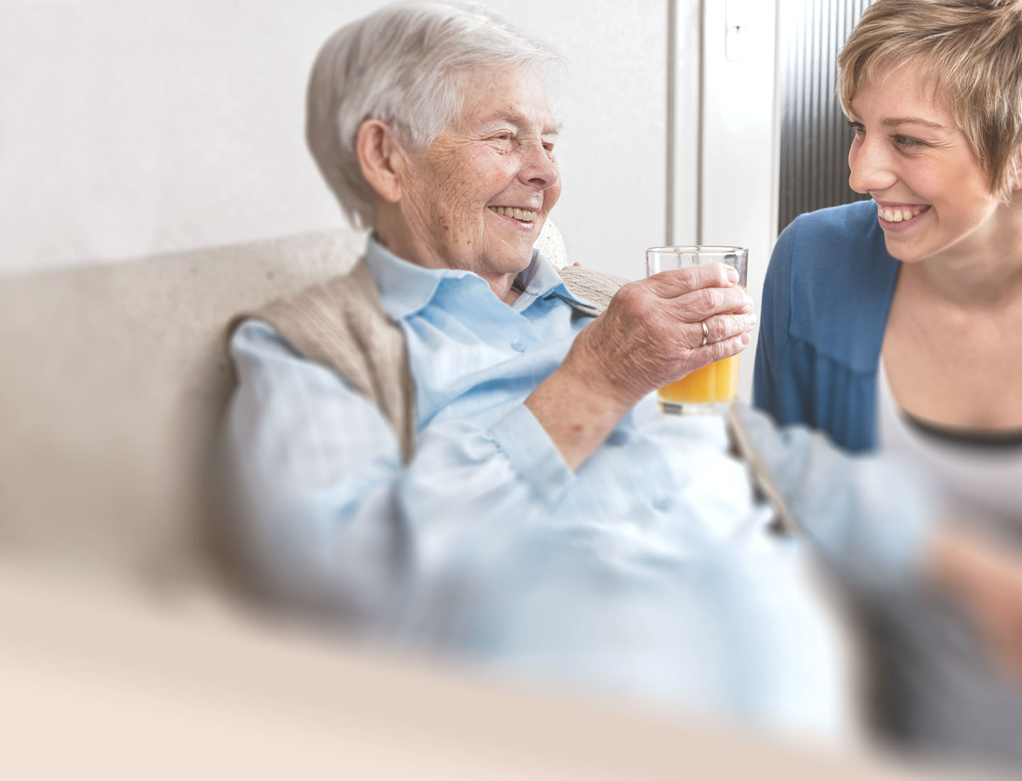 Seniorin und junge Frau trinken Orangensaft zusammen