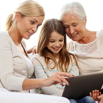Großmutter, Tochter und Enkelin sitzen zusammen mit einem Tablet