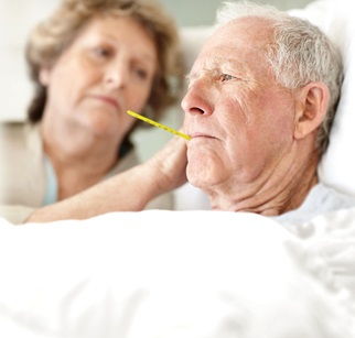 Seniorin und Pflegeperson betrachten Fieberthermometer