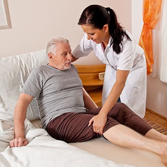 Pflegerin hilft Senior aus dem Bett
