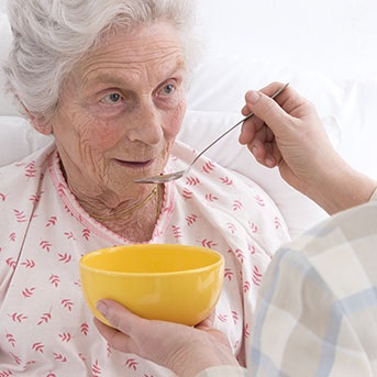 Bettlägerige Seniorin wird gefüttert