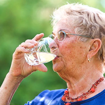 Seniorin trinkt aus Glas
