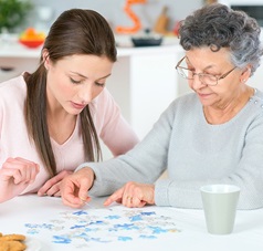 Seniorin puzzelt mit Pflegerin